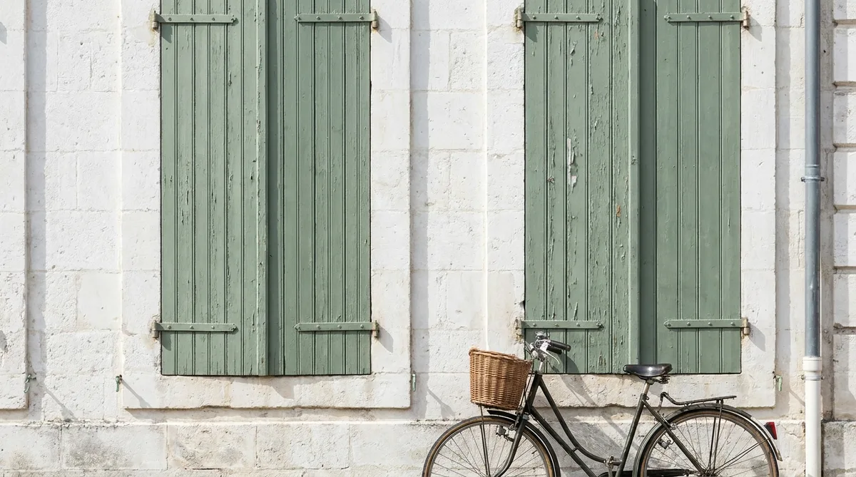 close up of traditional green wooden shutters on a white facade in Charente-Maritime with a vintage bicycle